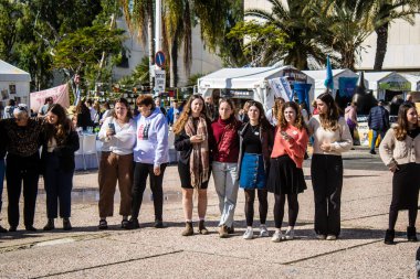 Tel Aviv, İsrail - 25 Ocak 2024 İsrailli gençler Tel Aviv 'deki Rehine Meydanı' nda hala Gazze 'de tutulan 100 rehinenin anısına şarkı söylüyorlar. İnsanlar düzenli olarak rehine ailelerini desteklemek için toplanır.