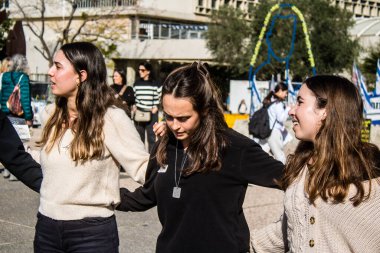 Tel Aviv, İsrail - 25 Ocak 2024 İsrailli gençler Tel Aviv 'deki Rehine Meydanı' nda hala Gazze 'de tutulan 100 rehinenin anısına şarkı söylüyorlar. İnsanlar düzenli olarak rehine ailelerini desteklemek için toplanır.