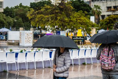 Tel Aviv, İsrail, 18 Şubat 2024 İsrail 'in sembolik ve simgesel şehri Tel Aviv sokaklarında şemsiyeyle yürüyen insanlar