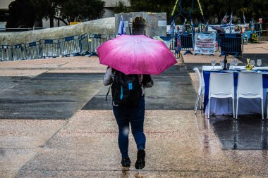 Tel Aviv, İsrail, 18 Şubat 2024 İsrail 'in sembolik ve simgesel şehri Tel Aviv sokaklarında şemsiyeyle yürüyen insanlar