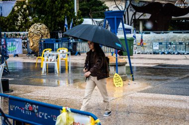 Tel Aviv, İsrail, 18 Şubat 2024 İsrail 'in sembolik ve simgesel şehri Tel Aviv sokaklarında şemsiyeyle yürüyen insanlar