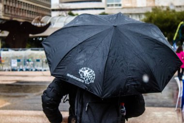 Tel Aviv, İsrail, 18 Şubat 2024 İsrail 'in sembolik ve simgesel şehri Tel Aviv sokaklarında şemsiyeyle yürüyen insanlar