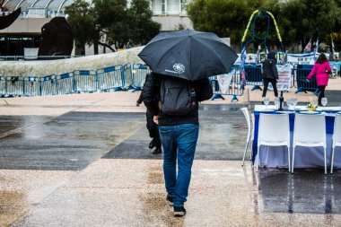 Tel Aviv, İsrail, 18 Şubat 2024 İsrail 'in sembolik ve simgesel şehri Tel Aviv sokaklarında şemsiyeyle yürüyen insanlar