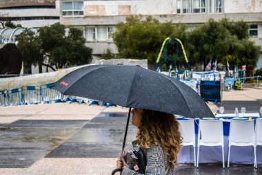 Tel Aviv, İsrail, 18 Şubat 2024 İsrail 'in sembolik ve simgesel şehri Tel Aviv sokaklarında şemsiyeyle yürüyen insanlar