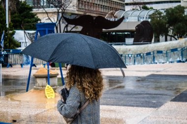 Tel Aviv, İsrail, 18 Şubat 2024 İsrail 'in sembolik ve simgesel şehri Tel Aviv sokaklarında şemsiyeyle yürüyen insanlar