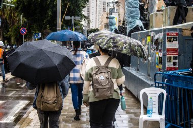 Tel Aviv, İsrail, 18 Şubat 2024 İsrail 'in sembolik ve simgesel şehri Tel Aviv sokaklarında şemsiyeyle yürüyen insanlar