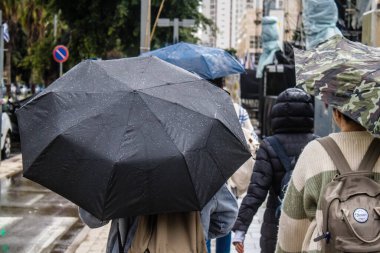 Tel Aviv, İsrail, 18 Şubat 2024 İsrail 'in sembolik ve simgesel şehri Tel Aviv sokaklarında şemsiyeyle yürüyen insanlar
