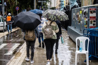 Tel Aviv, İsrail, 18 Şubat 2024 İsrail 'in sembolik ve simgesel şehri Tel Aviv sokaklarında şemsiyeyle yürüyen insanlar