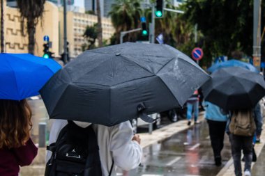 Tel Aviv, İsrail, 18 Şubat 2024 İsrail 'in sembolik ve simgesel şehri Tel Aviv sokaklarında şemsiyeyle yürüyen insanlar
