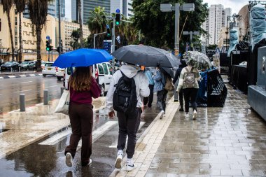 Tel Aviv, İsrail, 18 Şubat 2024 İsrail 'in sembolik ve simgesel şehri Tel Aviv sokaklarında şemsiyeyle yürüyen insanlar