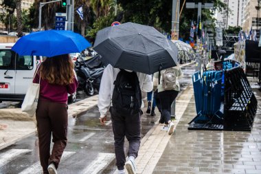 Tel Aviv, İsrail, 18 Şubat 2024 İsrail 'in sembolik ve simgesel şehri Tel Aviv sokaklarında şemsiyeyle yürüyen insanlar