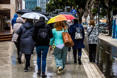 Tel Aviv, İsrail, 18 Şubat 2024 İsrail 'in sembolik ve simgesel şehri Tel Aviv sokaklarında şemsiyeyle yürüyen insanlar