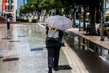Tel Aviv, İsrail, 18 Şubat 2024 İsrail 'in sembolik ve simgesel şehri Tel Aviv sokaklarında şemsiyeyle yürüyen insanlar