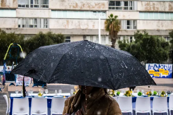 Tel Aviv, İsrail, 18 Şubat 2024 İsrail 'in sembolik ve simgesel şehri Tel Aviv sokaklarında şemsiyeyle yürüyen insanlar