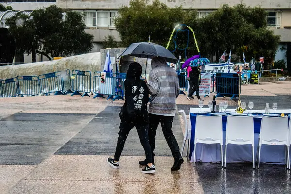 Tel Aviv, İsrail, 18 Şubat 2024 İsrail 'in sembolik ve simgesel şehri Tel Aviv sokaklarında şemsiyeyle yürüyen insanlar