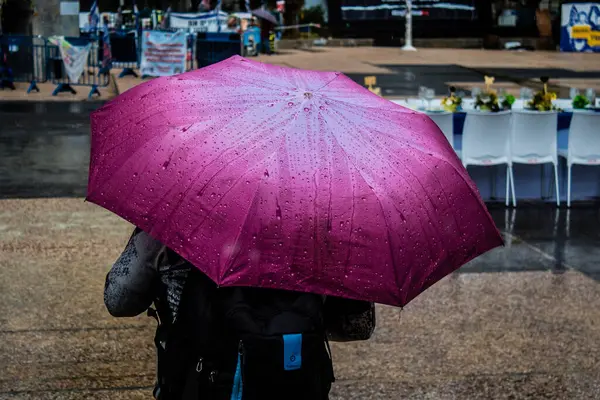 Tel Aviv, İsrail, 18 Şubat 2024 İsrail 'in sembolik ve simgesel şehri Tel Aviv sokaklarında şemsiyeyle yürüyen insanlar