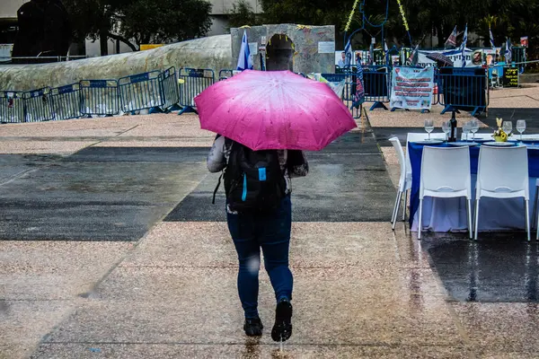 Tel Aviv, İsrail, 18 Şubat 2024 İsrail 'in sembolik ve simgesel şehri Tel Aviv sokaklarında şemsiyeyle yürüyen insanlar