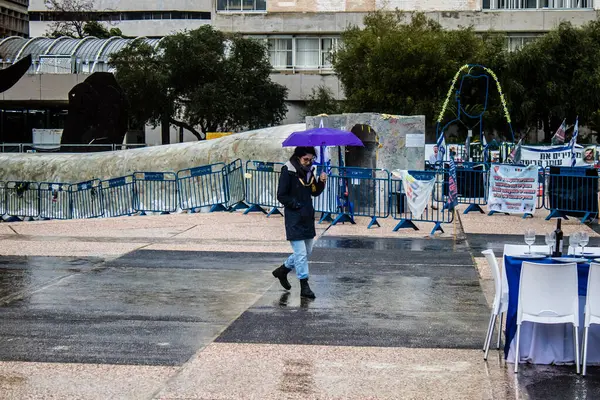 Tel Aviv, İsrail, 18 Şubat 2024 İsrail 'in sembolik ve simgesel şehri Tel Aviv sokaklarında şemsiyeyle yürüyen insanlar