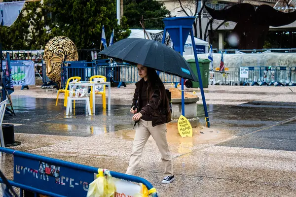 Tel Aviv, İsrail, 18 Şubat 2024 İsrail 'in sembolik ve simgesel şehri Tel Aviv sokaklarında şemsiyeyle yürüyen insanlar