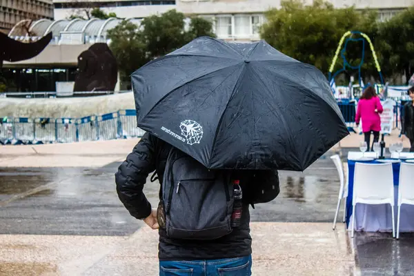 Tel Aviv, İsrail, 18 Şubat 2024 İsrail 'in sembolik ve simgesel şehri Tel Aviv sokaklarında şemsiyeyle yürüyen insanlar