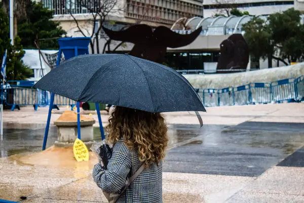 Tel Aviv, İsrail, 18 Şubat 2024 İsrail 'in sembolik ve simgesel şehri Tel Aviv sokaklarında şemsiyeyle yürüyen insanlar