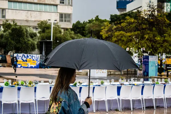 Tel Aviv, İsrail, 18 Şubat 2024 İsrail 'in sembolik ve simgesel şehri Tel Aviv sokaklarında şemsiyeyle yürüyen insanlar