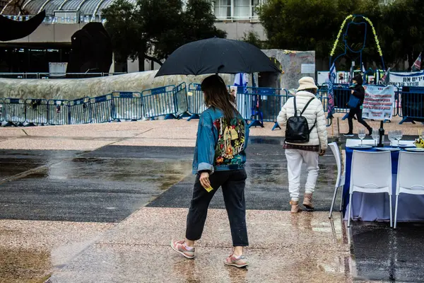 Tel Aviv, İsrail, 18 Şubat 2024 İsrail 'in sembolik ve simgesel şehri Tel Aviv sokaklarında şemsiyeyle yürüyen insanlar