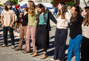 Tel Aviv, İsrail - 25 Ocak 2024 İsrailli gençler Tel Aviv 'deki Rehine Meydanı' nda hala Gazze 'de tutulan 100 rehinenin anısına şarkı söylüyorlar. İnsanlar düzenli olarak rehine ailelerini desteklemek için toplanır.