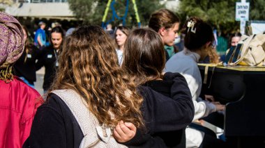 Tel Aviv, İsrail - 25 Ocak 2024 İsrailli gençler Tel Aviv 'deki Rehine Meydanı' nda hala Gazze 'de tutulan 100 rehinenin anısına şarkı söylüyorlar. İnsanlar düzenli olarak rehine ailelerini desteklemek için toplanır.