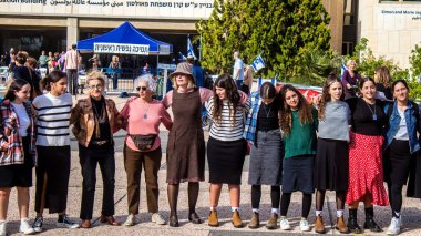 Tel Aviv, İsrail - 4 Ocak 2024 İsrailli gençler Tel Aviv 'deki Rehine Meydanı' nda hala Gazze 'de tutulan 129 rehinenin anısına şarkı söylüyorlar. İnsanlar düzenli olarak rehine ailelerini desteklemek için toplanır.