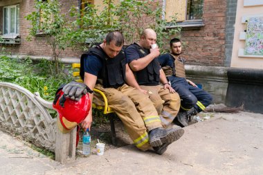 Kharkiv, Ukrayna, 01 Haziran 2024 İtfaiyeciler ve acil durum ekipleri Kharkiv 'de yıkılmış bir binanın yakınında dinleniyorlar.