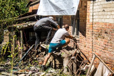 Derhachi, Ukrayna, 27 Haziran 2024 Derhachi kasabasındaki yıkılmış evlerin sakinleri Rus kuvvetlerinin güdümlü hava bombasıyla yaptığı saldırının ardından enkazı temizledi..