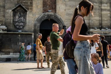 Lviv, Ukrayna, 18 Ağustos 2024 Lviv sakinleri ve turistler tarihi şehir merkezinde yürüyorlar. Ülke savaşta olmasına rağmen, çoğu işletme açık ve insanlar normal bir hayat yaşamaya çalışıyor..