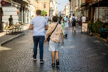 Lviv, Ukrayna, 18 Ağustos 2024 Lviv sakinleri ve turistler tarihi şehir merkezinde yürüyorlar. Ülke savaşta olmasına rağmen, çoğu işletme açık ve insanlar normal bir hayat yaşamaya çalışıyor..
