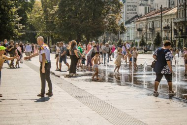 Lviv, Ukrayna, 22 Ağustos 2024 Çocuklar Lviv şehir merkezinde suyla oynuyorlar. Rusya 'yla savaş sırasında, Lviv binaları Rus füzeleri tarafından tehdit ediliyor ve hedef alınıyordu..