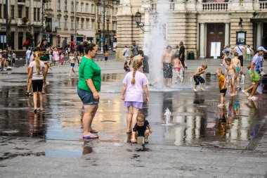 Lviv, Ukrayna, 22 Ağustos 2024 Çocuklar Lviv şehir merkezinde suyla oynuyorlar. Rusya 'yla savaş sırasında, Lviv binaları Rus füzeleri tarafından tehdit ediliyor ve hedef alınıyordu..