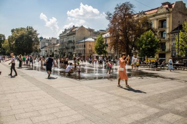 Lviv, Ukrayna, 22 Ağustos 2024 Çocuklar Lviv şehir merkezinde suyla oynuyorlar. Rusya 'yla savaş sırasında, Lviv binaları Rus füzeleri tarafından tehdit ediliyor ve hedef alınıyordu..