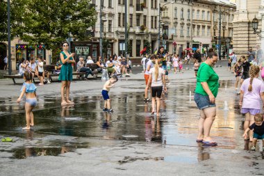 Lviv, Ukrayna, 22 Ağustos 2024 Çocuklar Lviv şehir merkezinde suyla oynuyorlar. Rusya 'yla savaş sırasında, Lviv binaları Rus füzeleri tarafından tehdit ediliyor ve hedef alınıyordu..