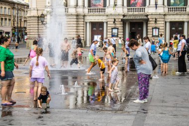 Lviv, Ukrayna, 22 Ağustos 2024 Çocuklar Lviv şehir merkezinde suyla oynuyorlar. Rusya 'yla savaş sırasında, Lviv binaları Rus füzeleri tarafından tehdit ediliyor ve hedef alınıyordu..