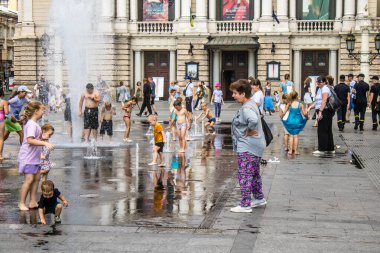 Lviv, Ukrayna, 22 Ağustos 2024 Çocuklar Lviv şehir merkezinde suyla oynuyorlar. Rusya 'yla savaş sırasında, Lviv binaları Rus füzeleri tarafından tehdit ediliyor ve hedef alınıyordu..