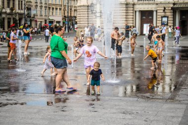 Lviv, Ukrayna, 22 Ağustos 2024 Çocuklar Lviv şehir merkezinde suyla oynuyorlar. Rusya 'yla savaş sırasında, Lviv binaları Rus füzeleri tarafından tehdit ediliyor ve hedef alınıyordu..