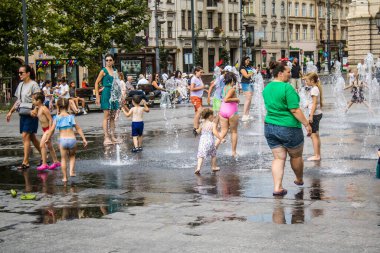 Lviv, Ukrayna, 22 Ağustos 2024 Çocuklar Lviv şehir merkezinde suyla oynuyorlar. Rusya 'yla savaş sırasında, Lviv binaları Rus füzeleri tarafından tehdit ediliyor ve hedef alınıyordu..