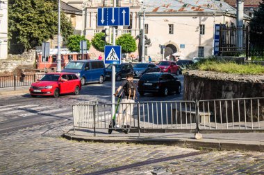 Lviv, Ukrayna, 25 Ağustos 2024. İnsanlar Lviv sokaklarında elektrikli scooterla geziyorlar. Küçük bir iç yanmalı motorlar ve merkezde bir güverte ile çalışıyorlar..