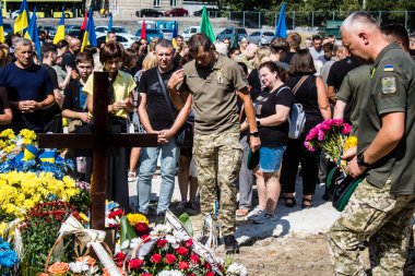 Lviv, Ukrayna, 29 Ağustos 2024 Mars meydanında, bir askeri mezarlık, askerler, silah arkadaşları, Rus ordusuna karşı savaşta ölen kendilerinden birinin mezarının önünde toplandı..