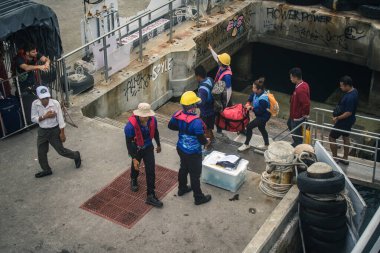 Koh Samui, Tayland, 5 Aralık 2024 Lompray feribot şirketi çalışanları yolcuları yolcu iskelesinde karşılıyor ve gemiyi kalkışa hazırlıyor. Çalışanlar turistlerin güvenliğini sağlıyor.