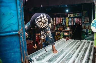Siem Reap, Kamboçya, 21 Ocak 2025 Buz teslimatçısı bir buz bloğunu bir mağazaya taşıdı. Kamboçya 'da elektrik kesintileri yaygın olduğu için, insanlar bu gıda koruma yöntemini kullanmayı tercih ediyorlar..