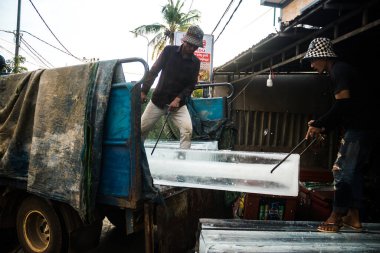Siem Reap, Kamboçya, 21 Ocak 2025 Buz teslimatçısı bir buz bloğunu bir mağazaya taşıdı. Kamboçya 'da elektrik kesintileri yaygın olduğu için, insanlar bu gıda koruma yöntemini kullanmayı tercih ediyorlar..