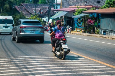 Koh Chang, Tayland, 15 Şubat 2025 Tayland 'da Koh Chang adasının sokaklarında motosikletli insanlar dolaşıyor. Canlı sokak hayatı, zengin kültür mirası ve hareketli pazarlarıyla ünlüdür.