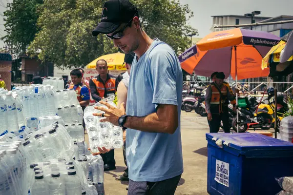 Bangkok, Tayland, 29 Mart 2025. Gönüllüler, Tayland 'daki deprem sonrası yıkılan yüksek binaların inşaatında kurtarma ekipleri için su şişeleri taşıyorlar..