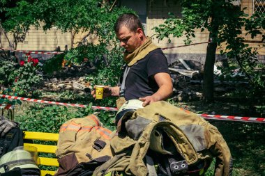 Kharkiv, Ukrayna, 7 Haziran 2025. İtfaiyeciler, Harkiv 'deki bir yerleşim yerine yapılan Rus saldırısından sonra dinleniyorlar. Birçok apartman yangını ve pencerenin tahrip olmasıyla hasar büyük..